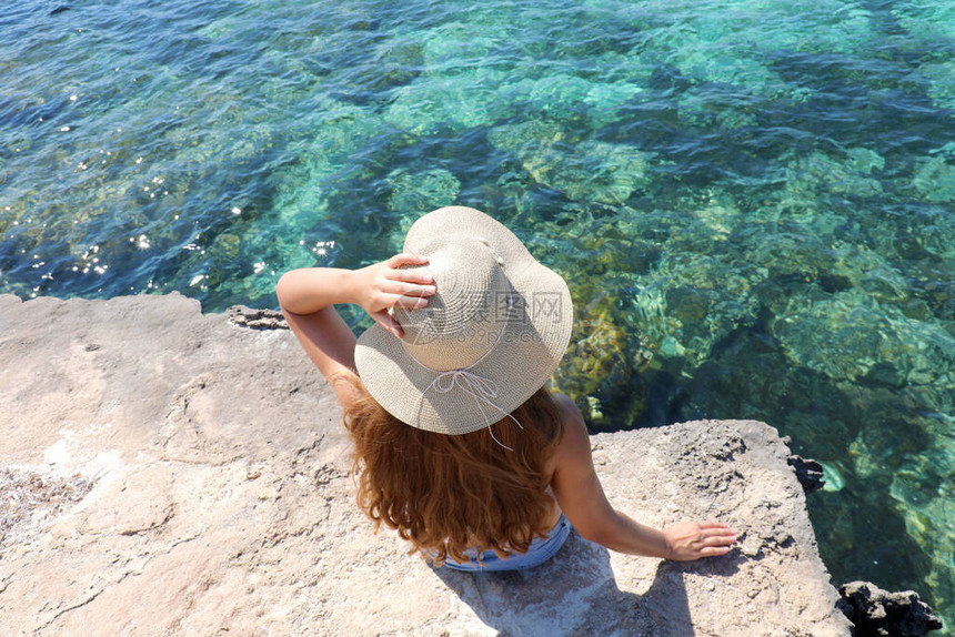 坐在海面悬崖上的年轻女子的夏季生活方式形象图片