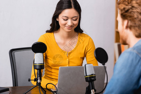 在电台演播室与男子访谈时使用笔记本电脑的棕色褐和亚裔广播图片