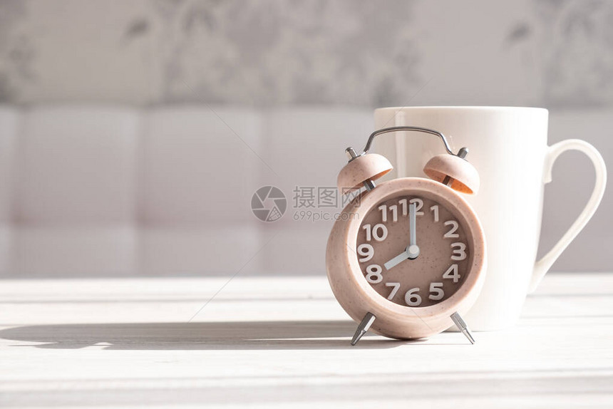一个闹钟和一杯咖啡的特写镜头有一个美好的早晨和早晨的阳光图片