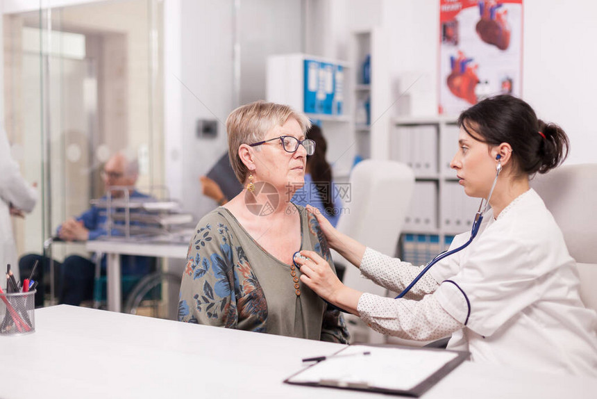 医生在医院办公室用听诊器检查老妇人的心跳坐在轮椅上的残疾老人在诊所走图片