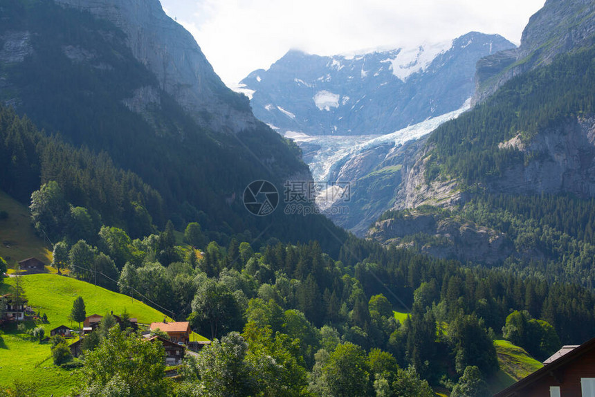 令人惊叹的瑞士高山景观绿色田野上的小木屋和背景雪峰的高山格林德瓦伯尔尼高地图片