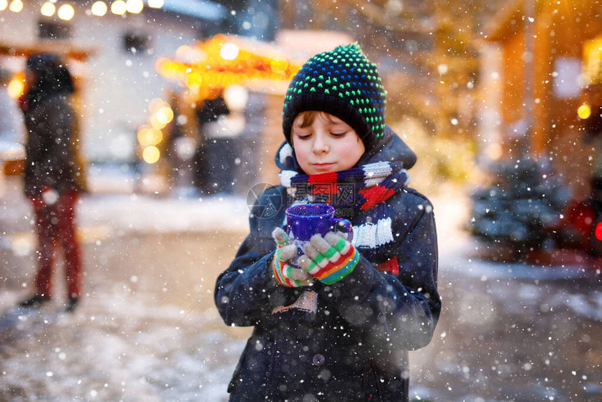 在德国圣诞市场上喝热儿童潘趣酒或巧克力的可爱小男孩图片