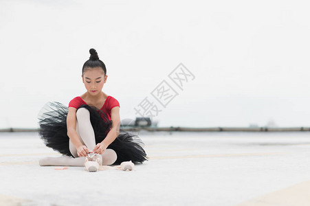 亚洲芭蕾舞女演员在练习芭蕾舞前系足尖鞋带图片