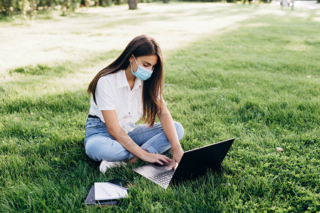 在流行病期间使用带外科口罩的笔记本电脑博主和聪明的工人学习和工作图片