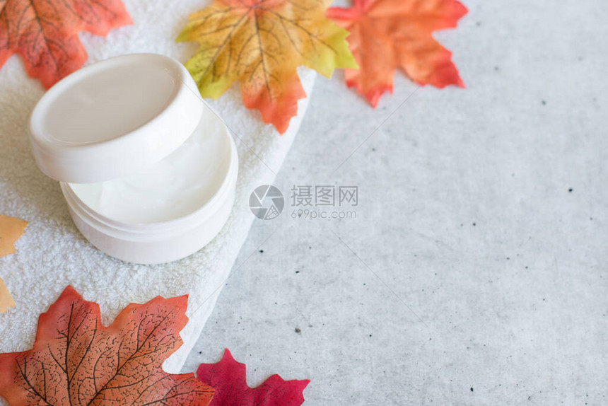 秋天护肤产品面霜或带有橙色和黄色亮叶子的体奶油图片