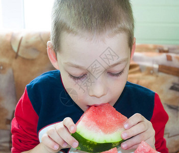 年轻男孩和一小片西瓜的照图片