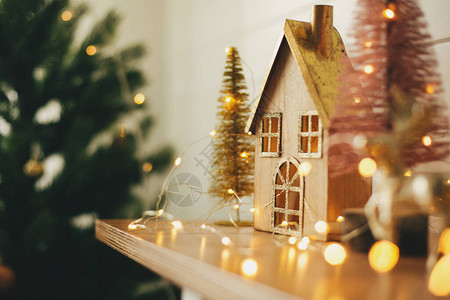 圣诞节快乐时尚的圣诞木屋闪发光的圣诞树和节日灯光下的驯鹿微型童话村背景图片