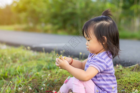 2岁婴儿的肖像图快乐的亚洲小女孩在花园里采摘和抚摸花草学习探索和图片