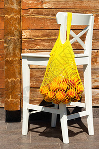 白椅子背上装着成熟桃子的网状袋或字符图片