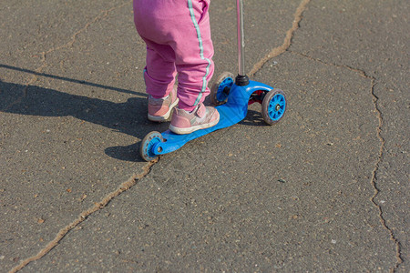 一个小孩在公园里学骑滑板车图片