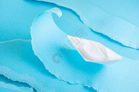 在模仿大海的蓝色纸片上折纸白船纸艺海上度假巡图片