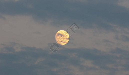 被称为鲟鱼月亮的8月橙色满月隐藏在蓝云背景纹理之后八月露娜图片