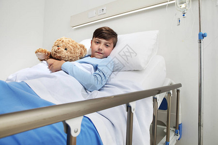 独自躺在医院房间里的可爱孩子的肖像与泰迪熊躺在床上图片