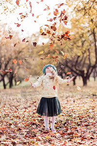 穿着贝雷帽黄色毛衣和秋天公园绿发短裙的漂亮小女孩图片