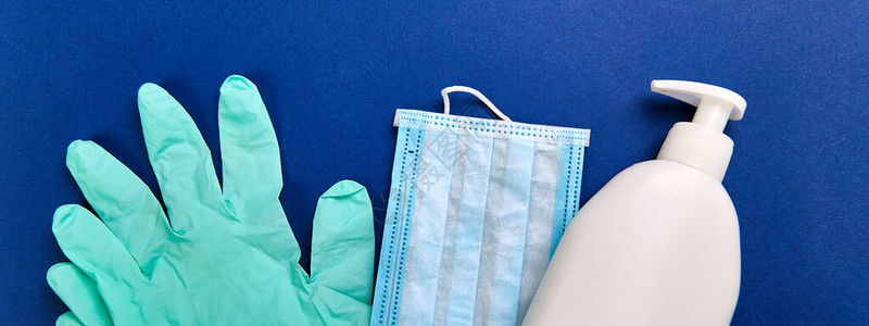 蓝色背景白袋中的防护医用口罩消毒凝胶和手套针对头孢细菌平躺的保护措图片