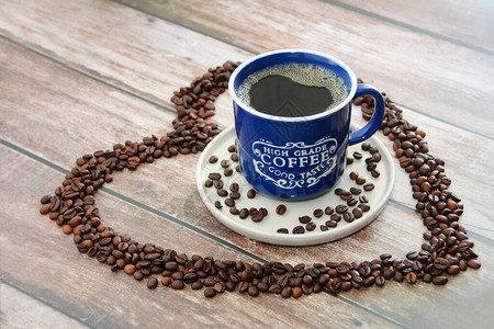 杯子里的咖啡饮料和心形的黑咖啡豆图片