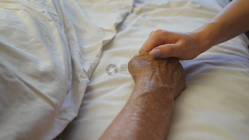 女孩在诊所里握着和安慰生病的成熟女人的手孙女轻抚摸躺在病床医院的奶皱巴的手臂女儿对母亲图片