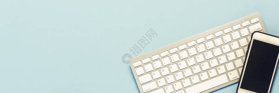 蓝色背景上的键盘和白色手机经营理念办公室工作移动应用程序和网站横幅图片