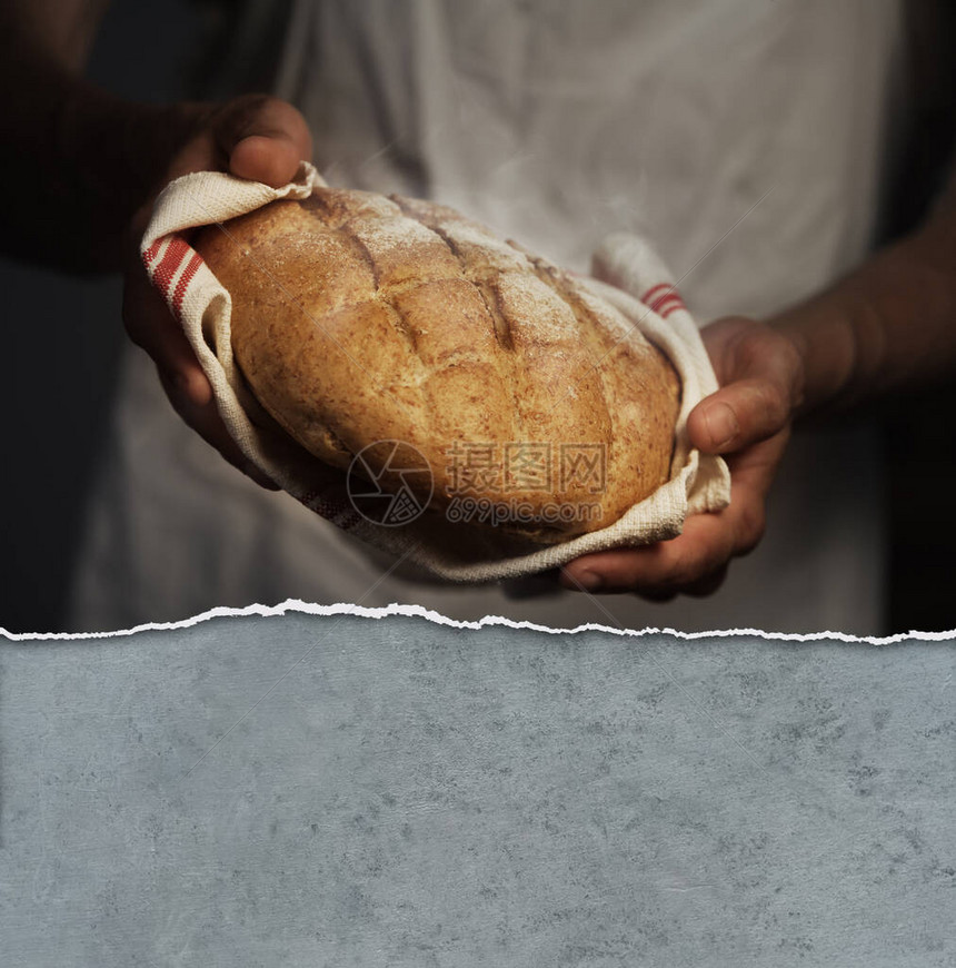 拿着一个温暖的面包的贝克人图片