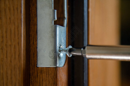 关闭修理门锁的木匠安装门把手杂工拧紧门铰链修理工的手有螺丝刀的锁匠将图片