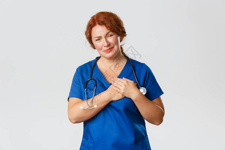 感动而富有同情心的红发护士中年医生或穿着磨砂膏的医生图片