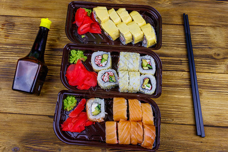 木桌上的塑料盒酱油和筷子套寿司卷顶视图寿司用于外卖或在塑料容图片