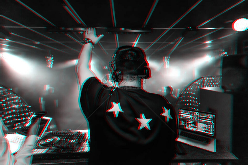 在电子音乐会上用耳机举起手的男DJ背部带有虚拟现实故障效应图片