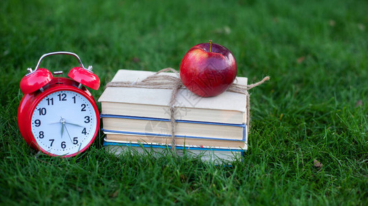 秋季早晨公园里的红色闹钟和旧书堆放教育理念和阅读图片