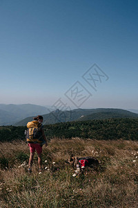 一个女孩旅行者和她的德国牧羊犬站在一座小山上图片