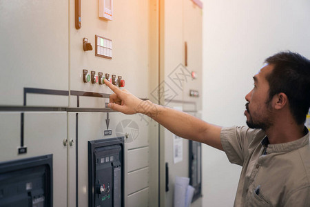 低压配电柜电气工程师在控制室配电柜检查电压和测试背景