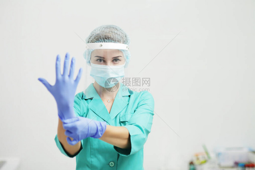 穿着制服医用口罩面罩的女医生或护士戴上手套冠状COVID19图片