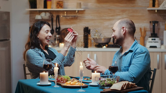 英俊的男人在节日晚宴上向他的女朋友求婚图片