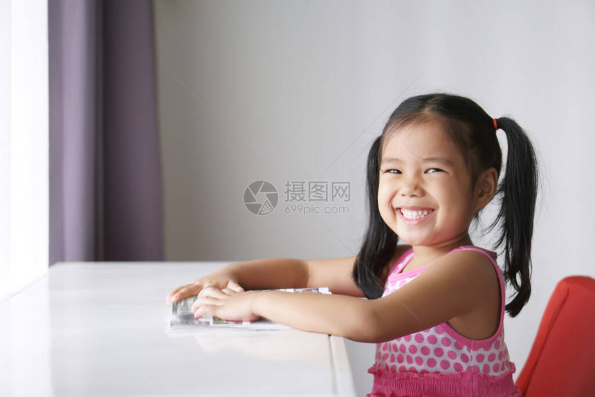 亚洲儿童或小女孩微笑或学生喜欢阅读书籍图片