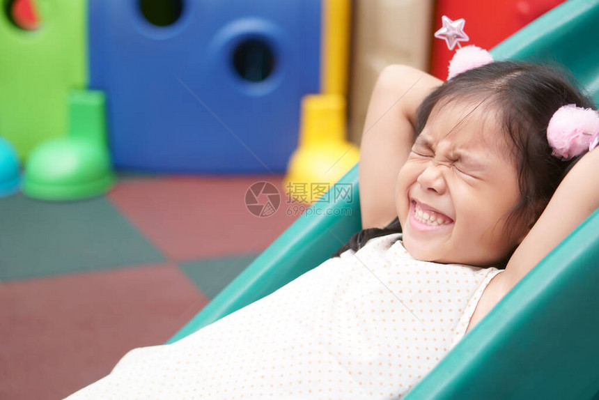亚洲儿童或小女孩微笑着闭上眼睛玩彩色滑块和快乐的趣或愉快的假期享受在操场或游乐园和带百货商店的托儿图片