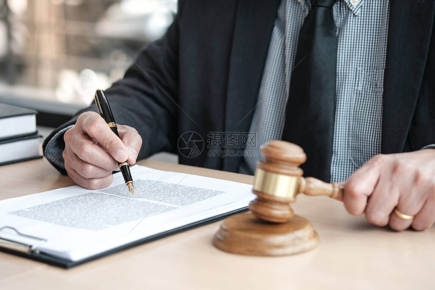 法律顾问向客户出示带有木槌和法律的已签署合同正图片