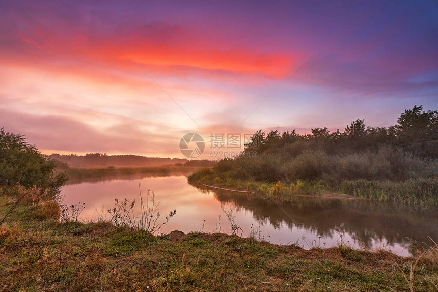 河雾秋日出多彩的黎明多云的日出黄昏秋天的颜色有草和灌木的河岸白俄图片