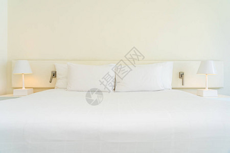 白色舒适的枕头和床上带灯的毯子图片
