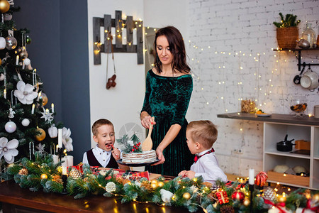 开心快乐的妈和两个男孩圣诞蛋糕在圣诞树图片