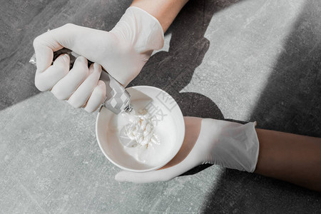 一个戴着白色防护手套的女孩将染发剂挤入氧化剂中工作中的调色师特写护发膜背景图片