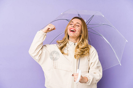 年轻的金发女人拿着雨伞孤立年轻的金发女人拿着雨伞孤立在胜利后举起拳图片