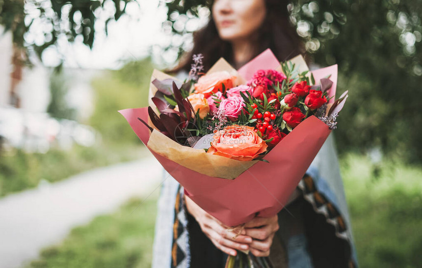 穿披风和牛仔裤的黑发年轻女人用红色调装着各种花图片