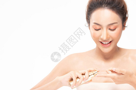 美丽的亚洲女人拿着瓶装化妆品奶油图片