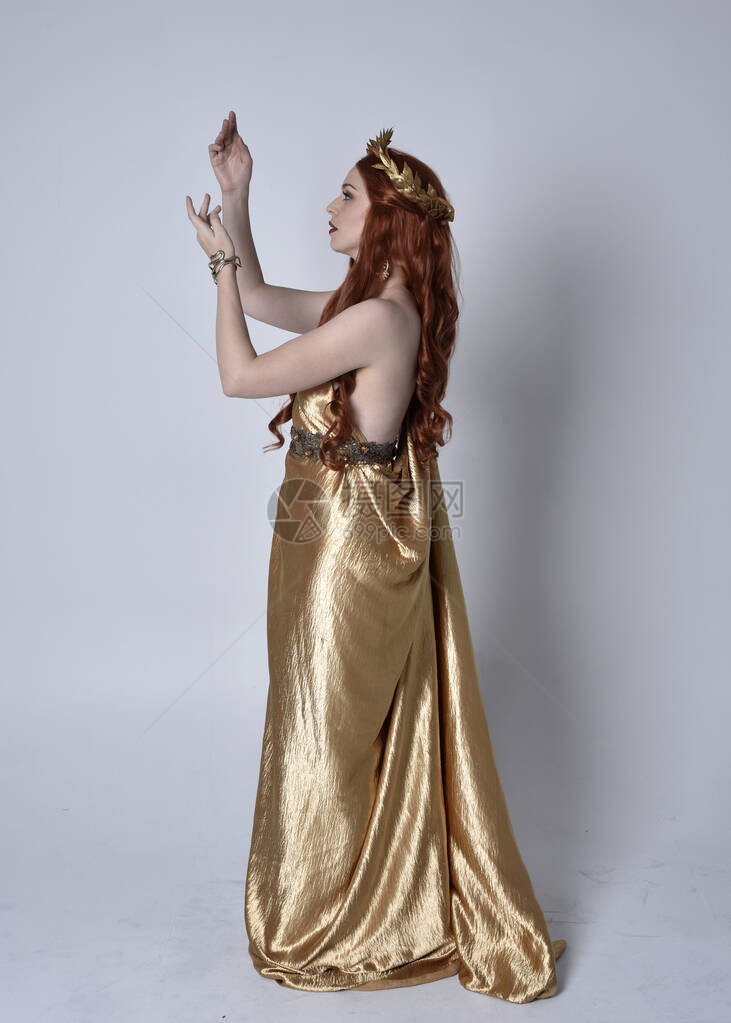 身穿长的希腊长袍和金色花圈的红头发女孩的全长肖像图片