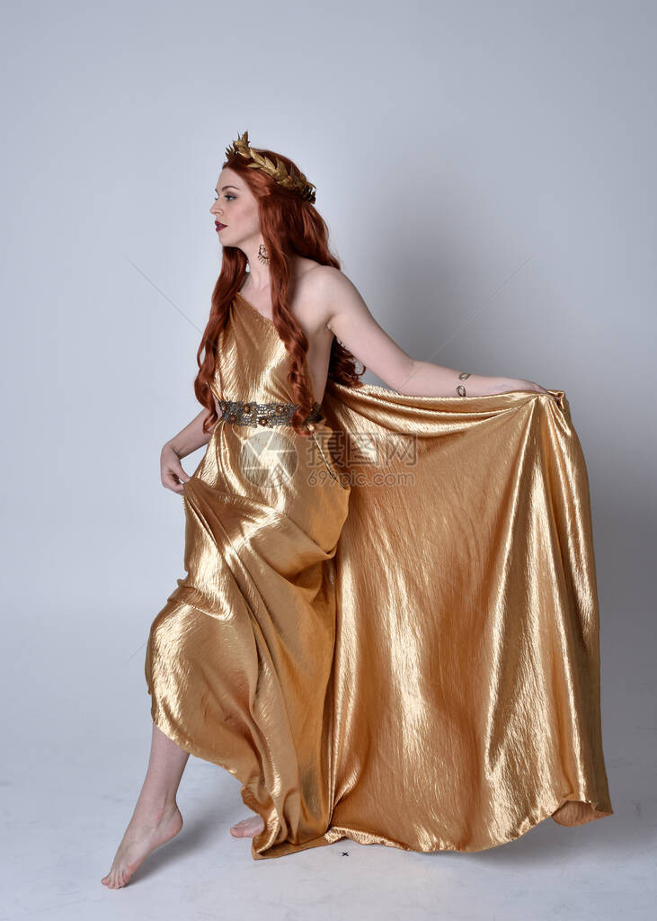 身穿长的希腊长袍和金色花圈的红头发女孩的全长肖像图片