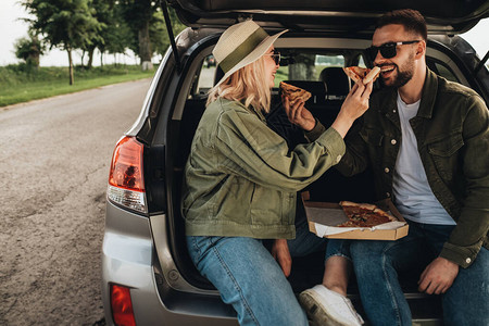 男人和女人坐在汽车后备箱里吃披萨图片