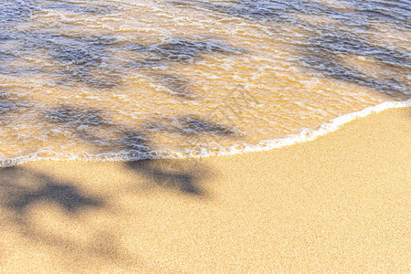 温暖海滩沙上的泡沫和水晶清晰的海浪图片