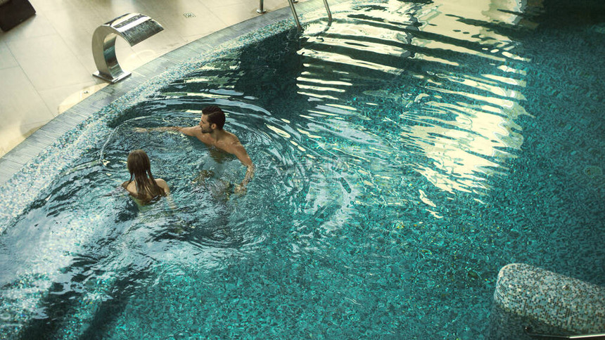 快乐的夫妇在室内游泳池游泳的视图上方美丽的夫妇一起在游泳池里放松快乐的男人和女人在豪华酒图片