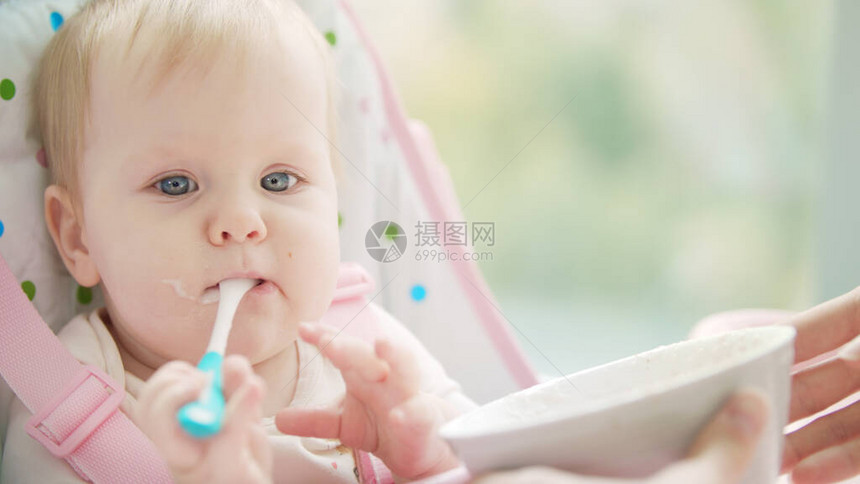 小女孩玩勺子宝吃勺子小孩在婴儿椅上从碗里啃勺子可爱图片