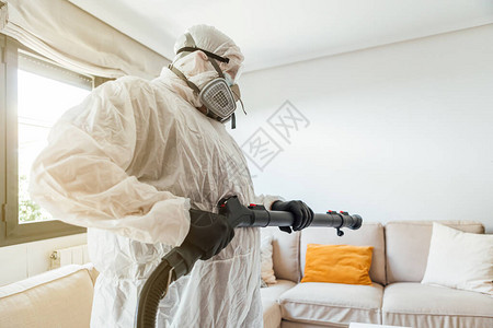穿着PPE的男子用COVID19消毒机对房子的客厅进行消毒大流行图片