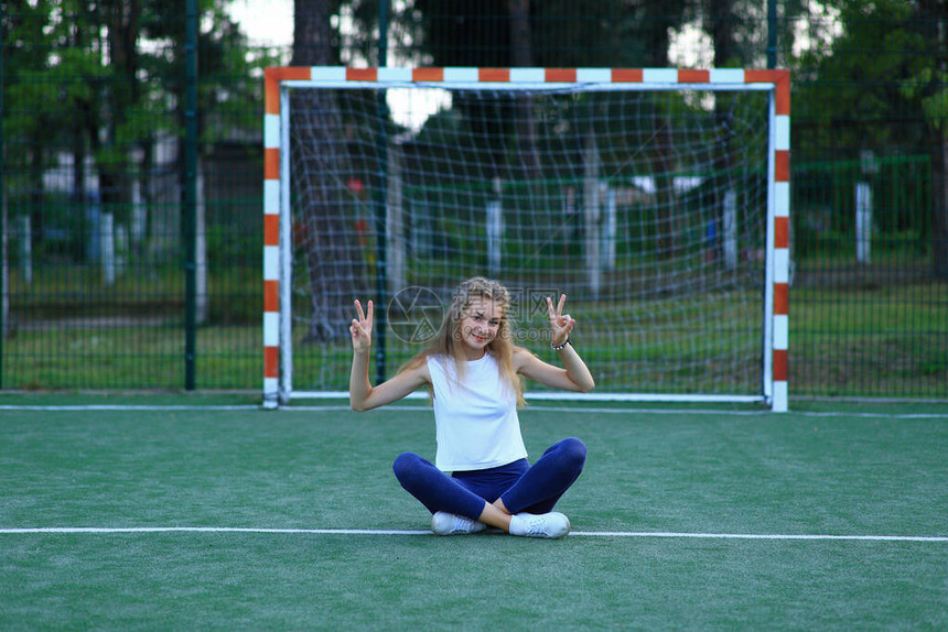 一名女孩在体育场近足球目标附近摆姿图片